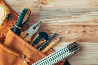A tool belt filled with tools on a wooden table.